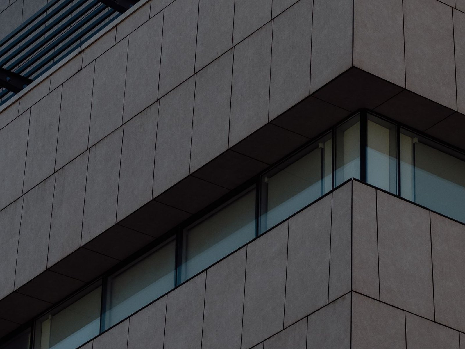 Architectural detail of a dark commercial facade where two glazed elevations meet