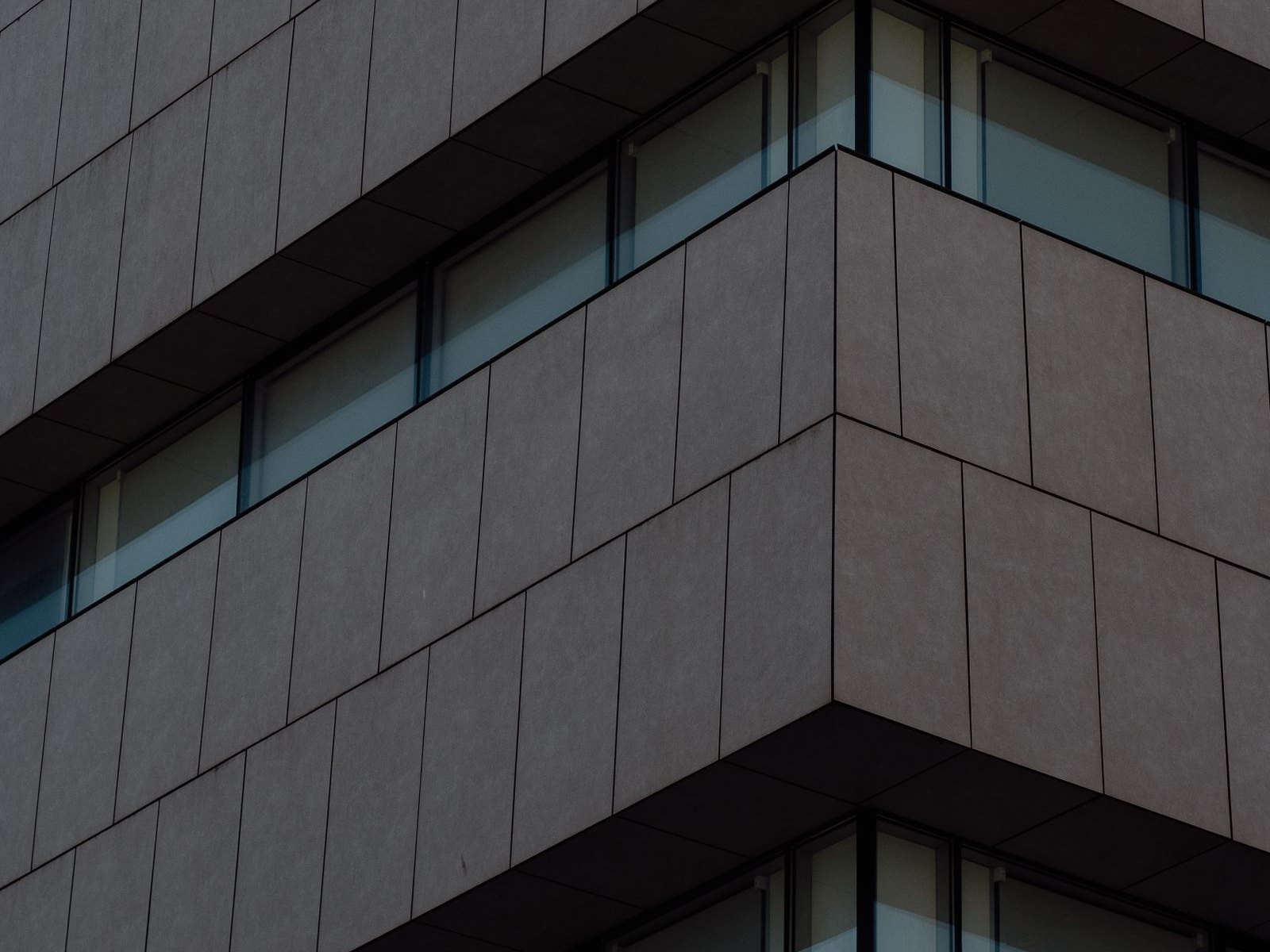Corner of a dark-clad commercial building with horizontal bands of windows