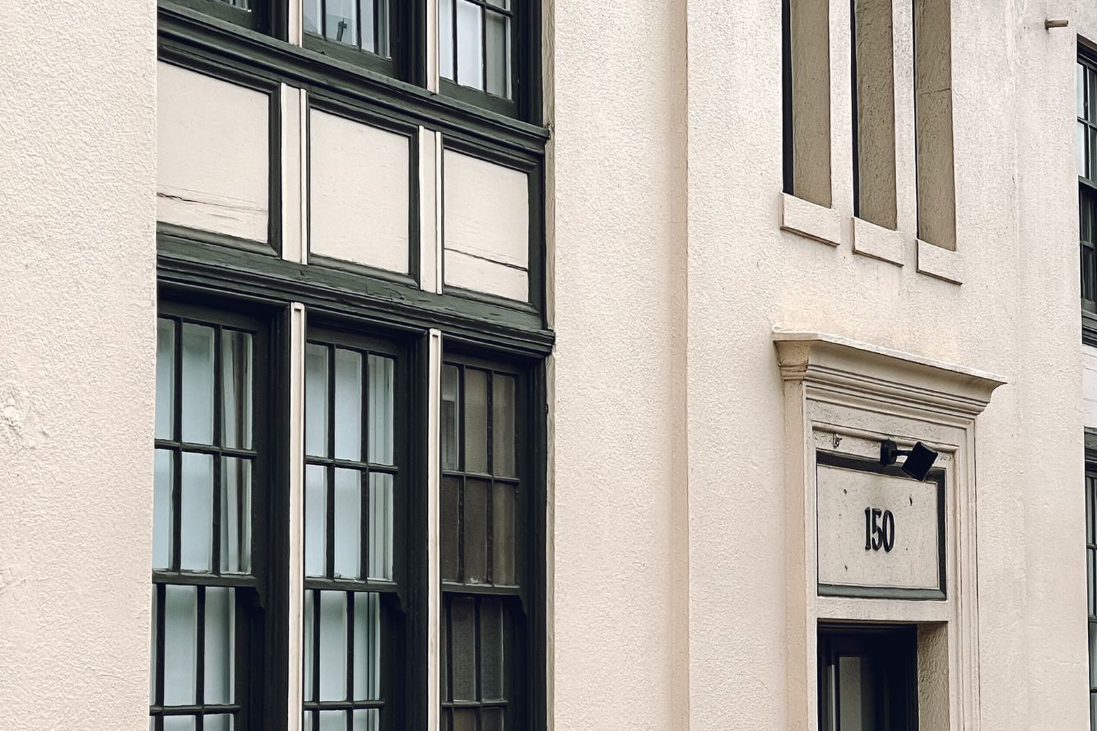 Tall window bays and entry surround on a plain rendered building front