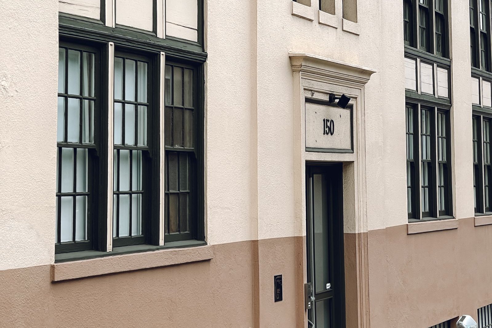 Street-level detail of a low-rise commercial facade with an entry door and tall windows