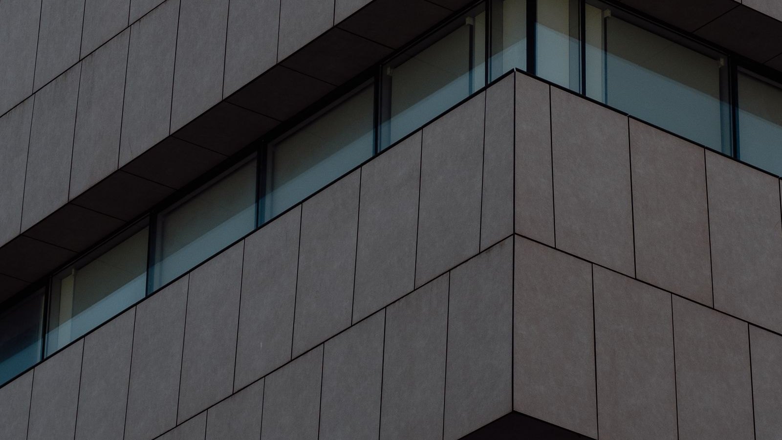 Dark-clad commercial building corner with continuous window bands
